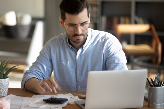 Man reviewing costs with a calculator and laptop