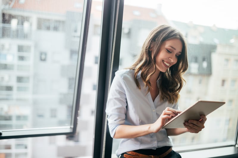 Woman by a window checking a tablet